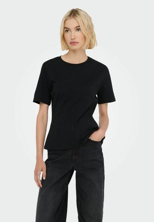 Top negru cu mânecă scurtă, guler rotund, design ajustat și material texturat. Asortat cu blugi negri largi, mâinile așezate în buzunare.