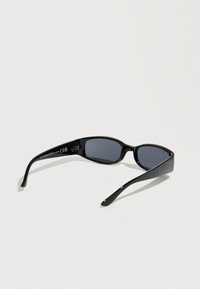 Μαύρα γυαλιά ηλίου με κομψό, επιμηκυμένο σχέδιο. Διαθέτουν γκρί φακούς και ομαλά πλαστικά πλαίσια. Περιλαμβάνει πιστοποίηση CE στο εσωτερικό του βραχίονα.