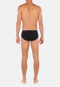 Svarta bomullsboxershorts med ett elastiskt midjeband med brandlogotyp, vy från baksidan som visar en jämn yta och figurnära design.