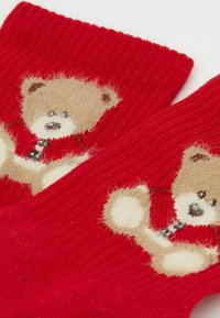 Red knitted mittens featuring a fuzzy tan bear design on each, with textured fabric and fine ribbing along the cuffs.