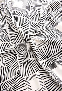 Zwart-wit stoffen patroon met een geometrisch ontwerp met scherpe lijnen en variërende diktes tegen een witte achtergrond.