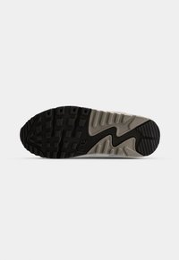Nike sporta apavu zole ar teksturētu melnu gumijas ārējo zoli, pelēku vidējo zoli ar viļņotu dizainu un izteiktu zīmolu uz papēža zonas.
