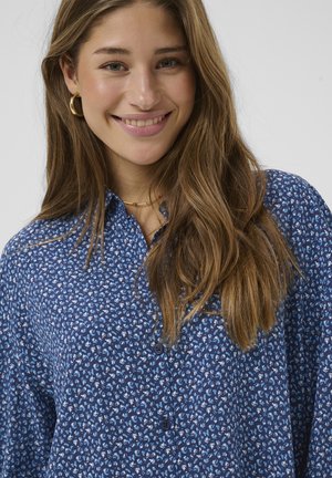 Blå mønstret bluse med lille blomsterdesign, knaplukning og krave. Glat stoftekstur med en afslappet pasform.