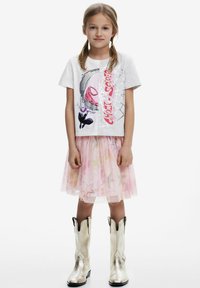 Grå t-shirt med grafiskt tryck, tillsammans med en rosa tyllkjol med stjärnmönster och glänsande silverfärgade cowboystövlar.