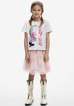 Graues T-Shirt mit Grafikdruck, kombiniert mit einem rosa Tüllrock mit Sternmustern und glänzenden silbernen Cowboy-Stiefeln.