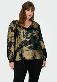 Blusa astratta nera e dorata con motivo, maniche lunghe con polsini elasticizzati e scollatura a V, realizzata in tessuto testurizzato. Abbinata a pantaloni neri.