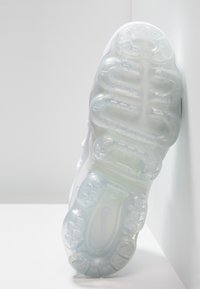 White Nike sneaker sole featuring translucent cushioning pods and textured surface, with a prominent swoosh logo near the heel.