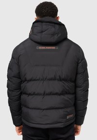 Schwarze gepolsterte Jacke mit Kapuze, featuring einem Logo-Patch und horizontalem Steppmuster auf dem Rücken. Weicher Stoff und warmes Design.