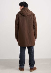 Chestnutkleurige waterdichte parka met een capuchon, met een rechte snit, gladde textuur en een zoom die onder de taille valt.
