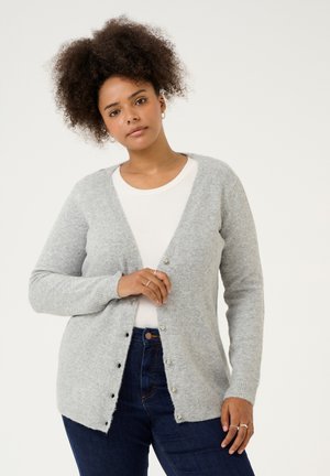 Gray knit cardigan with a v-neck, button front, and ribbed cuffs. Worn over a light-colored top and paired with dark denim jeans.