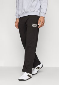 Crne trenirke s "Juventus" grafikom u bijeloj boji, izrađene od mekog materijala s opuštenim krojem i suženim nogavicama.