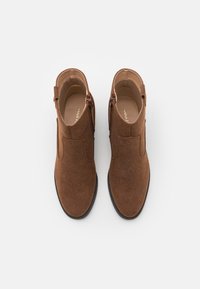 Ruske suède gležnjače s niskim potpeticama, bočnim patentnim zatvaračima i elastičnim panelima za lako obuvanje. Glatka unutrašnjost i teksturirana potplata.