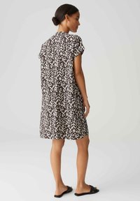 Kurzärmeliges Kleid in braun und weißem abstrakten Muster, knielang, aus leichtem Stoff mit einer einfachen, lässigen Silhouette.