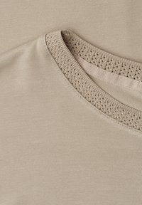 Pull beige col rond avec un col côtelé texturé et un tissu tricoté lisse, présenté à plat sur un fond assorti.