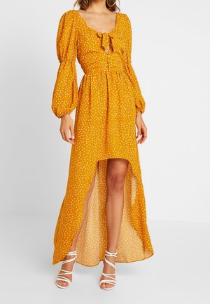 Gele maxi-jurk met witte stippen, een vierkante halslijn, pofmouwen en een voorsplit. Gemaakt van lichtgewicht stof met een gladde textuur.