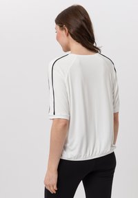 Weißes T-Shirt mit kurzen Ärmeln und schwarzen Seitenstreifen, mit rundem Ausschnitt und elastischem Saum. Glattes Material, lockere Passform.