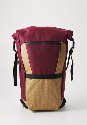 Maroon and beige roll-top backpack with front zip pocket, black strap across front, and adjustable side straps.