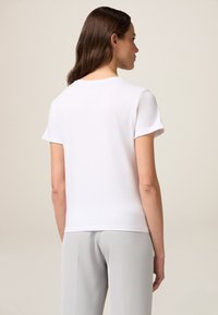 Witte korte mouw t-shirt met een ronde hals, voorzien van opgerolde mouwen. Het materiaal lijkt zacht en zit aansluitend op het lichaam.
