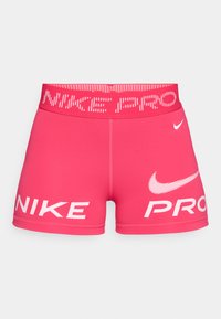 Ružové športové šortky s širokým pásom s logom. Na prednej strane sú výrazné biele nápisy "NIKE" a "PRO" a materiál je hladký a elastický.
