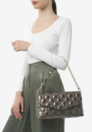 Sac à main matelassé gris métallique avec une bandoulière en chaîne, doté d'une fermeture à rabat et d'un motif floral en relief ; tenu par un mannequin portant un haut blanc.
