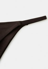 Čierne dno bikín z látky s preloženým okrajom a tenkým pásikom na bielom pozadí.