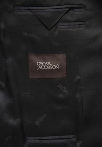 Svart satin kappa med ett brunt märke där det står "Oscar Jacobson" broderat i vitt. Inkluderar fickor med satinbesättning.