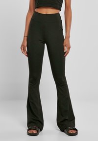 Leggings noires évasées en tissu doux et extensible. Design taille haute avec une ceinture lisse. Légère évasement du genou à l'ourlet.