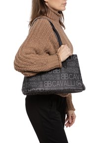 Zwarte totebag met een reliëf logo-ontwerp. Zachte textuur met dubbele handvaten, rechthoekige vorm en ruime binnenkant.