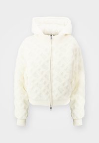 Vit kort jacka med ett strukturerat diamantmönster. Har dragkedja framtill, stor huva och ribbade ärmslut och nederkant. Slät, mjuk material.