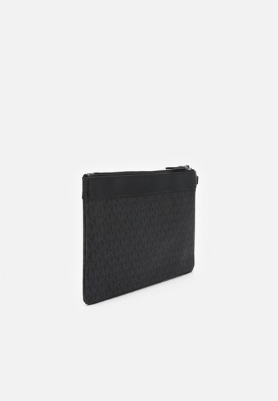 Pochette noire fine avec motif subtil répété "MK", fermeture éclair sur le dessus et bordure en cuir lisse le long du bord supérieur.