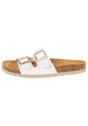 White sandal with two adjustable straps, gold buckles, and a cork footbed. Textured sole for grip, contoured shape for comfort.