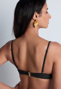 Haut de bikini noir avec des bretelles ajustables et un support en or à l'arrière. Texture de tissu lisse, design minimaliste, mettant en valeur une silhouette de dos plat.