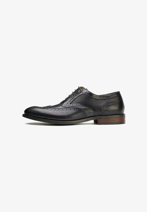 Black leather dress shoe with wingtip design, smooth texture, detailed brogue perforations, and a round toe. Wooden heel with subtle branding.