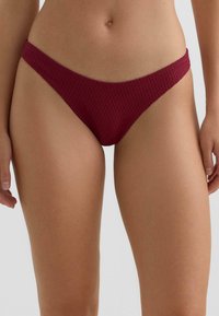 Bordové plavkové nohavičky s textúrovaným vzorom, nízkym pásom a úzkymi bočnými remienkami pre minimálne zakrytie.