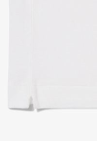 Polo bianco realizzato in tessuto piqué dalla consistenza testurizzata, con orlo spaccato e maniche corte. Design del colletto semplice, senza loghi o motivi visibili.