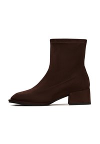 Boots de gleznă sintetice de culoare maro, cu vârf ascuțit, toc bloc de înălțime medie și textură netedă, având un detaliu simplu de cusătură de-a lungul marginii superioare.