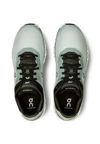 Hellgrüne Laufschuhe mit schwarzen Schnürsenkeln, ausgestattet mit einem strukturierten Obermaterial, Logo-Akzenten und einer gepolsterten Sohle mit markanten weißen Details.