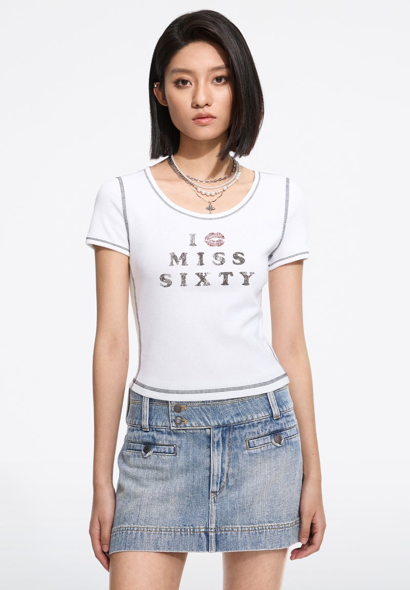 Top alb cu mânecă scurtă, având textul "I ♥ MISS SIXTY" în argintiu și roșu, asociat cu o fustă mini din denim de un albastru deschis, cu două nasturi.