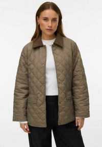 Veste matelassée en brun discret avec un col contrastant de couleur brun foncé, dotée de boutons-pression et de poches latérales, idéale pour une tenue décontractée.