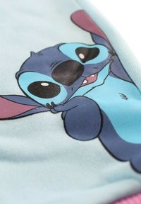 Tissu bleu présentant un personnage de dessin animé avec de grandes oreilles, des yeux proéminents et une expression souriante, sur un fond aqua clair.