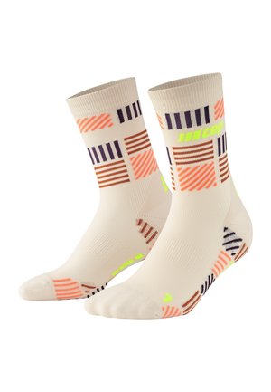 Knielange Socken in hellem Beige, mit bunten horizontalen und vertikalen Streifen in Orange, Braun und Marineblau. Neonakzent-Logo.