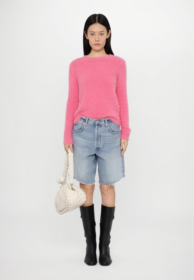 Jersey rosa fuzzy, pantalones cortos de mezclilla azules con dobladillo deshecho, botas negras hasta la rodilla y un bolso trenzado crema. Conjunto simple y casual.