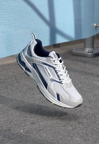 Pantofi sport gri și albaștri, cu un superior din plasă, accente bleumarin și o talpă texturată, având șireturi și branding pe lateral.