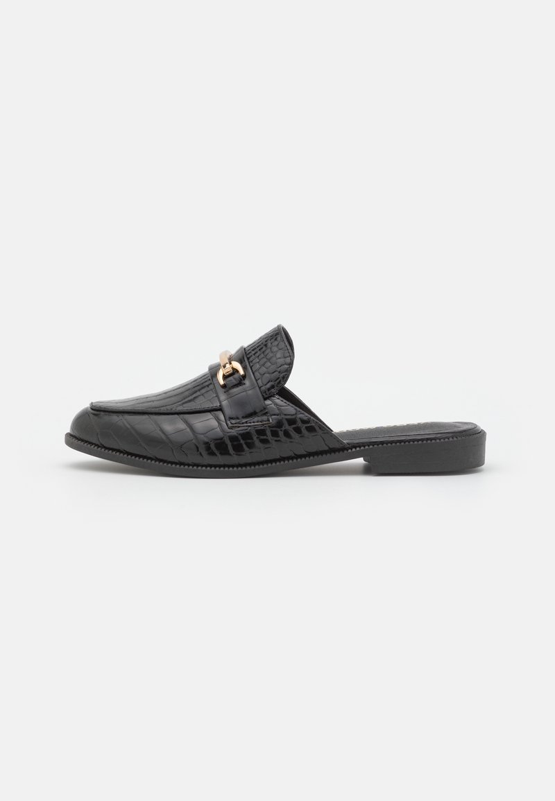 Mule noire en cuir synthétique imitation crocodile, à enfiler, avec un petit talon et un détail en métal doré sur le dessus.