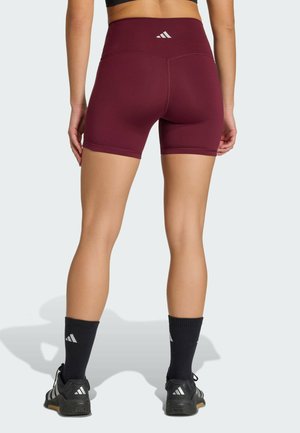 Kastanjebrunne atletikshorts lavet af strækstof, med høj talje og diskrete sømdetaljer. Kombineret med sorte strømper og sko.