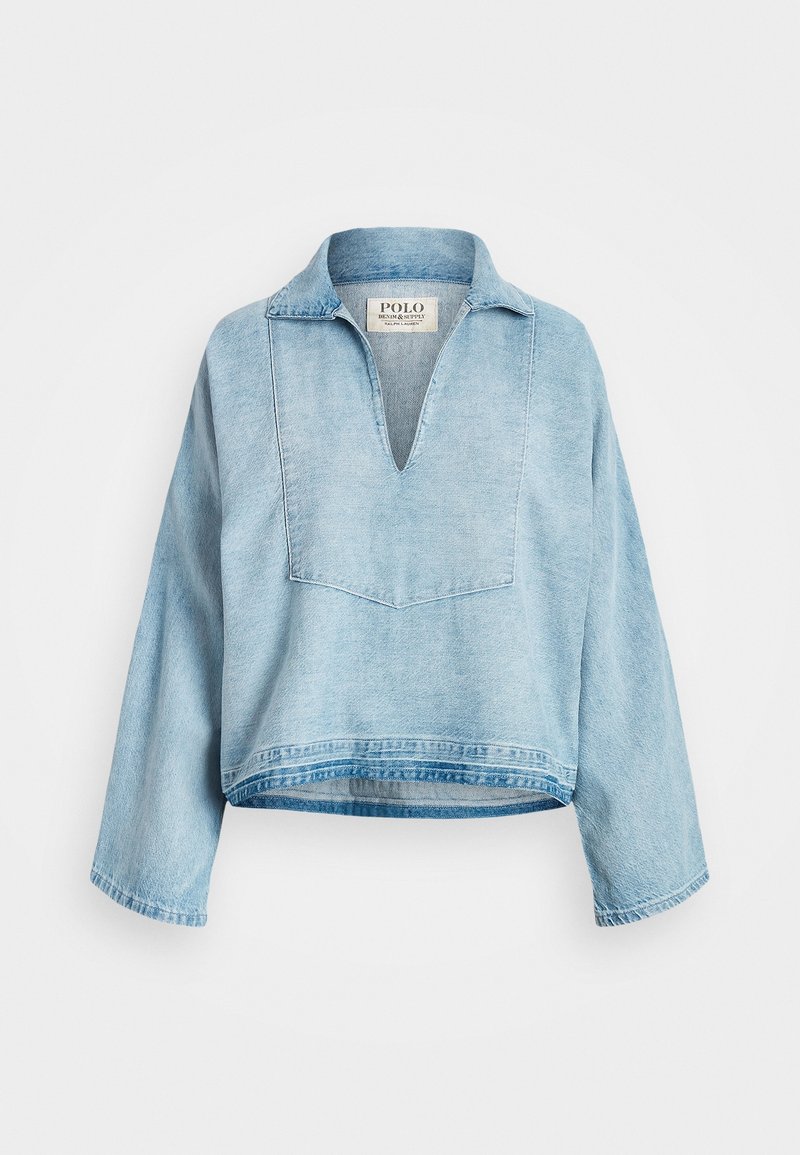 Pull en denim bleu clair à manches longues avec un large col en V et une coupe décontractée, avec une étiquette Polo Denim & Supply à l’intérieur du col.