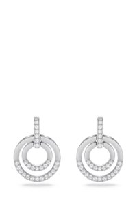 Boucles d'oreilles circulaires en argent composées de plusieurs anneaux entrelacés, ornées de petits cristaux transparents le long du bord inférieur de chaque anneau.