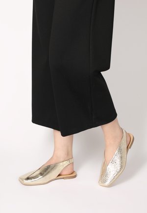 Goldene Slingback-Schuhe mit zwei unterschiedlichen Texturen: glatt und geprägt, mit einer flachen Holzsohle und einem offenen Zehendesign.