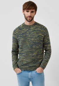 Sweter dzianinowy w niebiesko-zielony melanż, z okrągłym dekoltem, długimi rękawami i fakturowanym wykończeniem, noszony z jasnoniebieskimi jeansami.