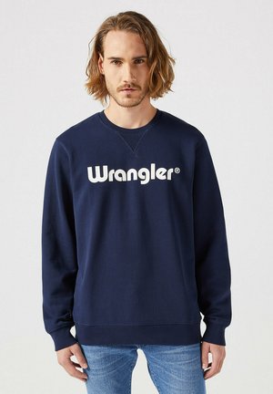 Granatowa bluza z bawełny, z białym logo "Wrangler" na piersi. Długie rękawy i okrągły dekolt z prążkowanymi mankietami.